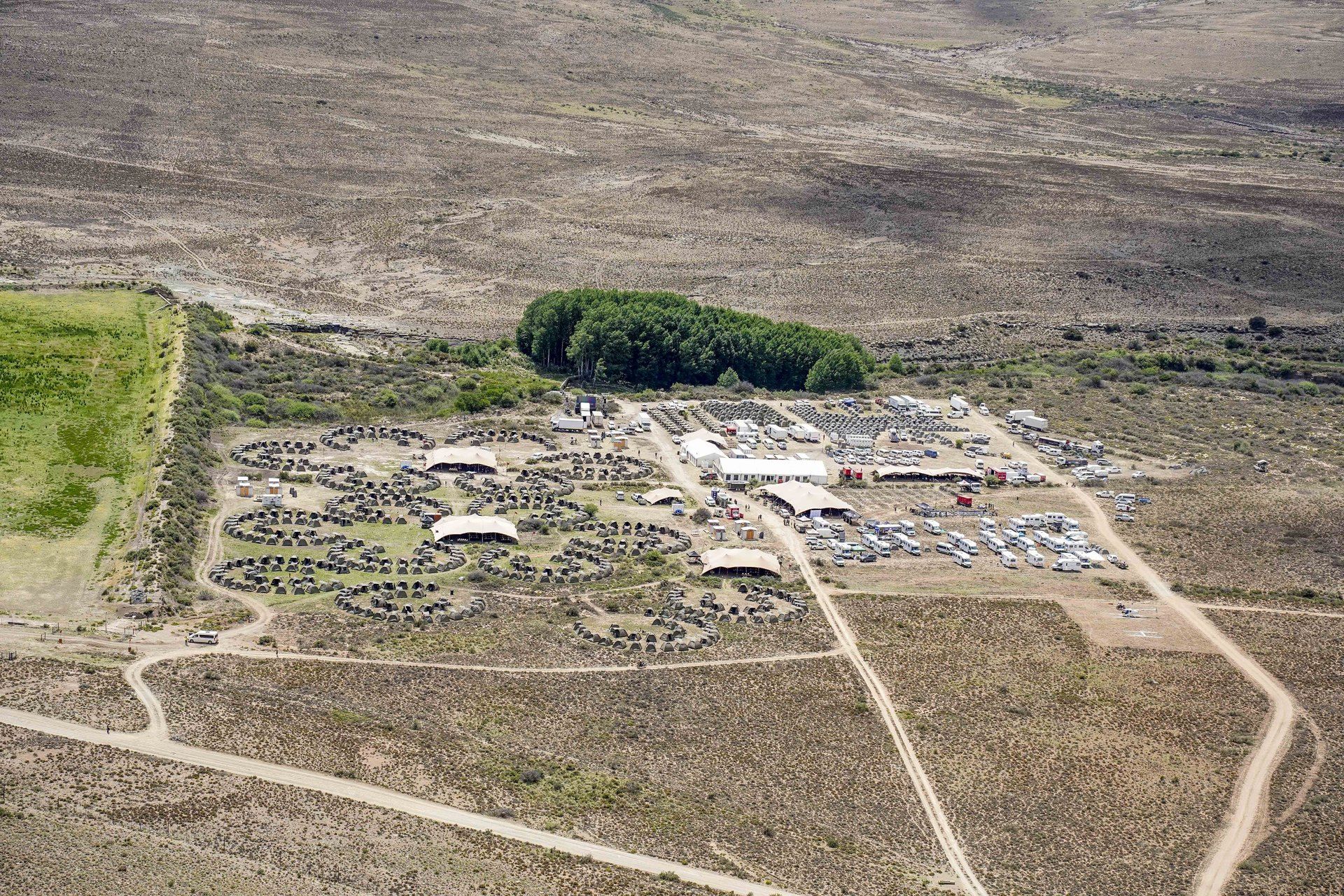 A whole Burn Camp seen from the air by day: circles of tents, stretch tents and motorhomes on the open Karoo plain