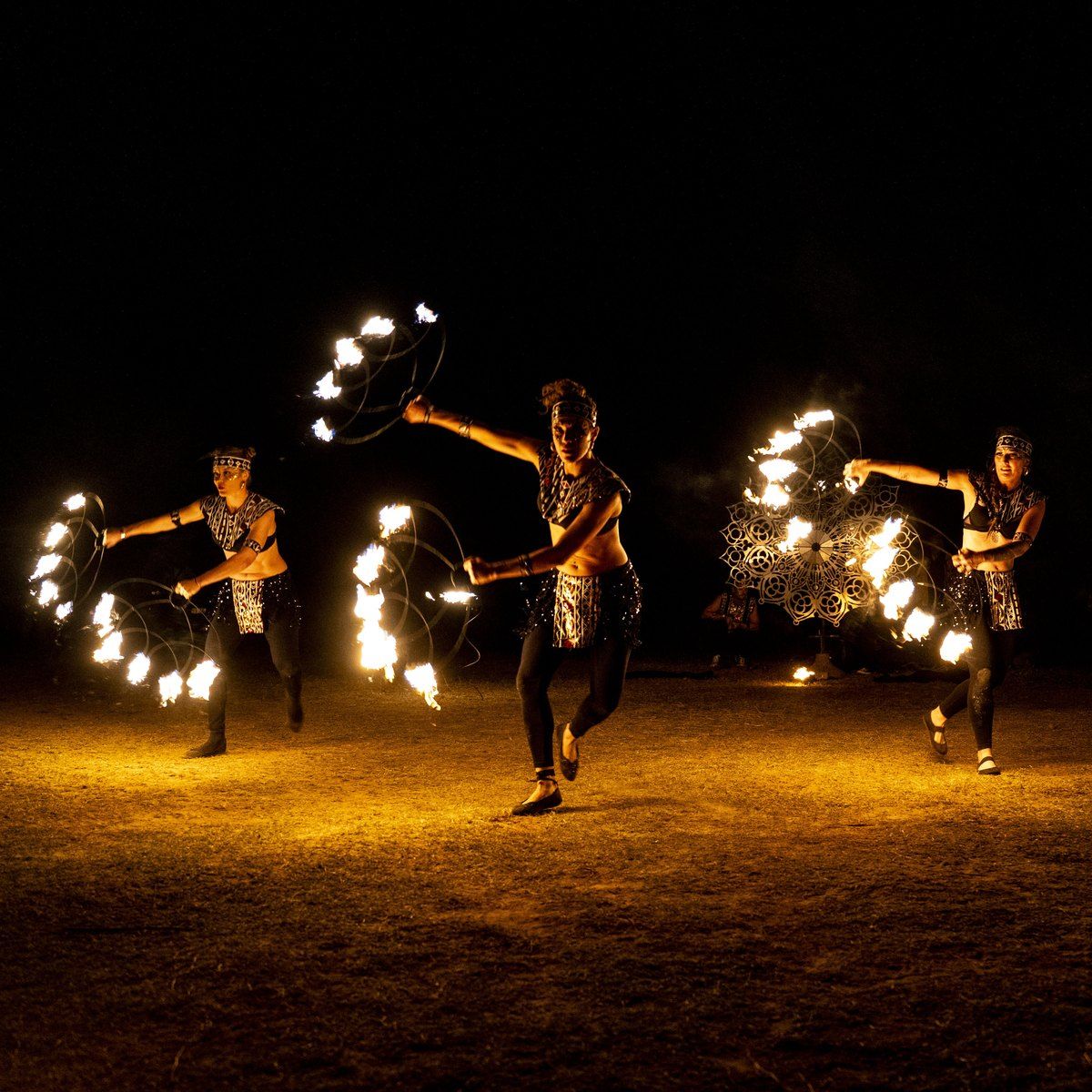 Fire dancers spinning flaming hoops at night