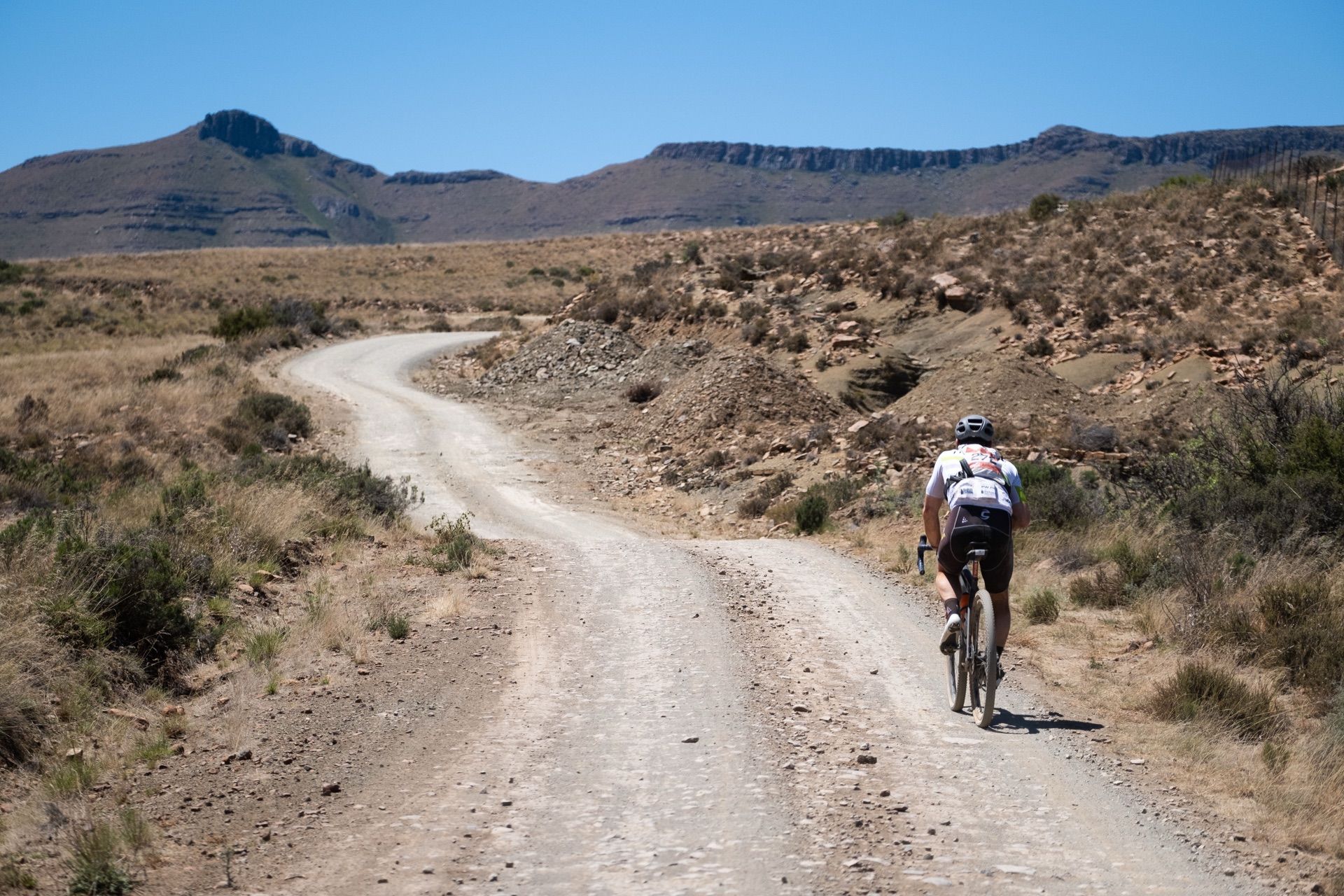 A rider on a winding gravel road through dry hills