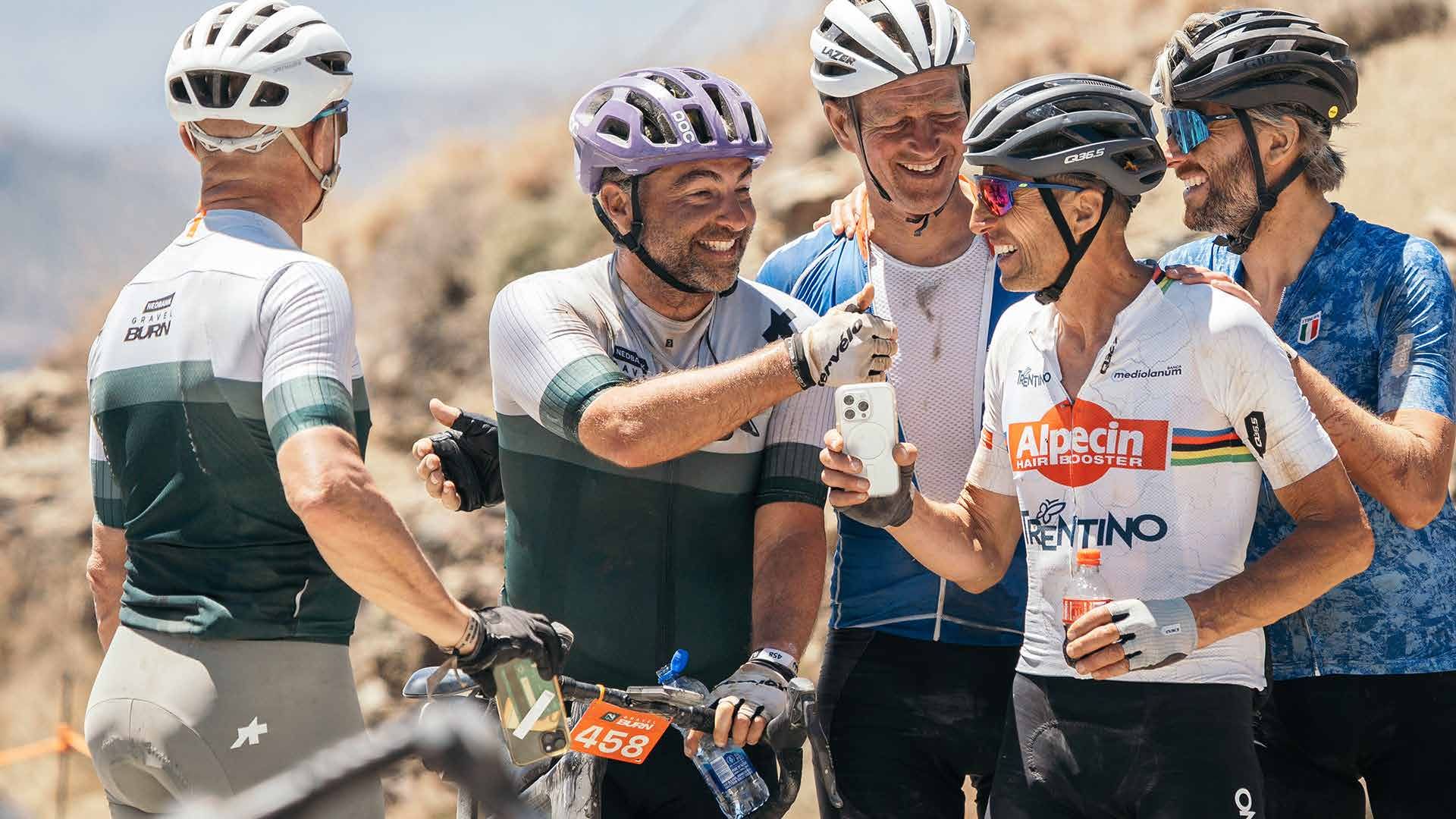 Maurizio Fondriest, in his rainbow-trimmed jersey, sharing photos on his phone with other riders