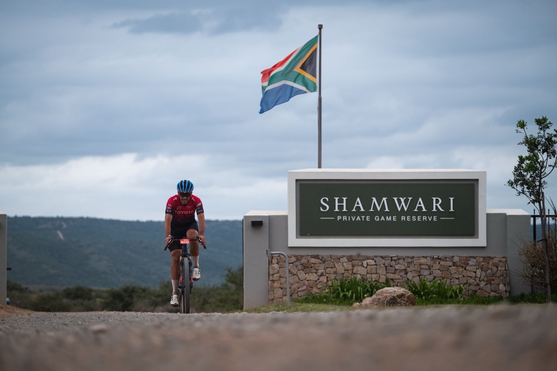 A rider passing the Shamwari Private Game Reserve gate, with the South African flag above