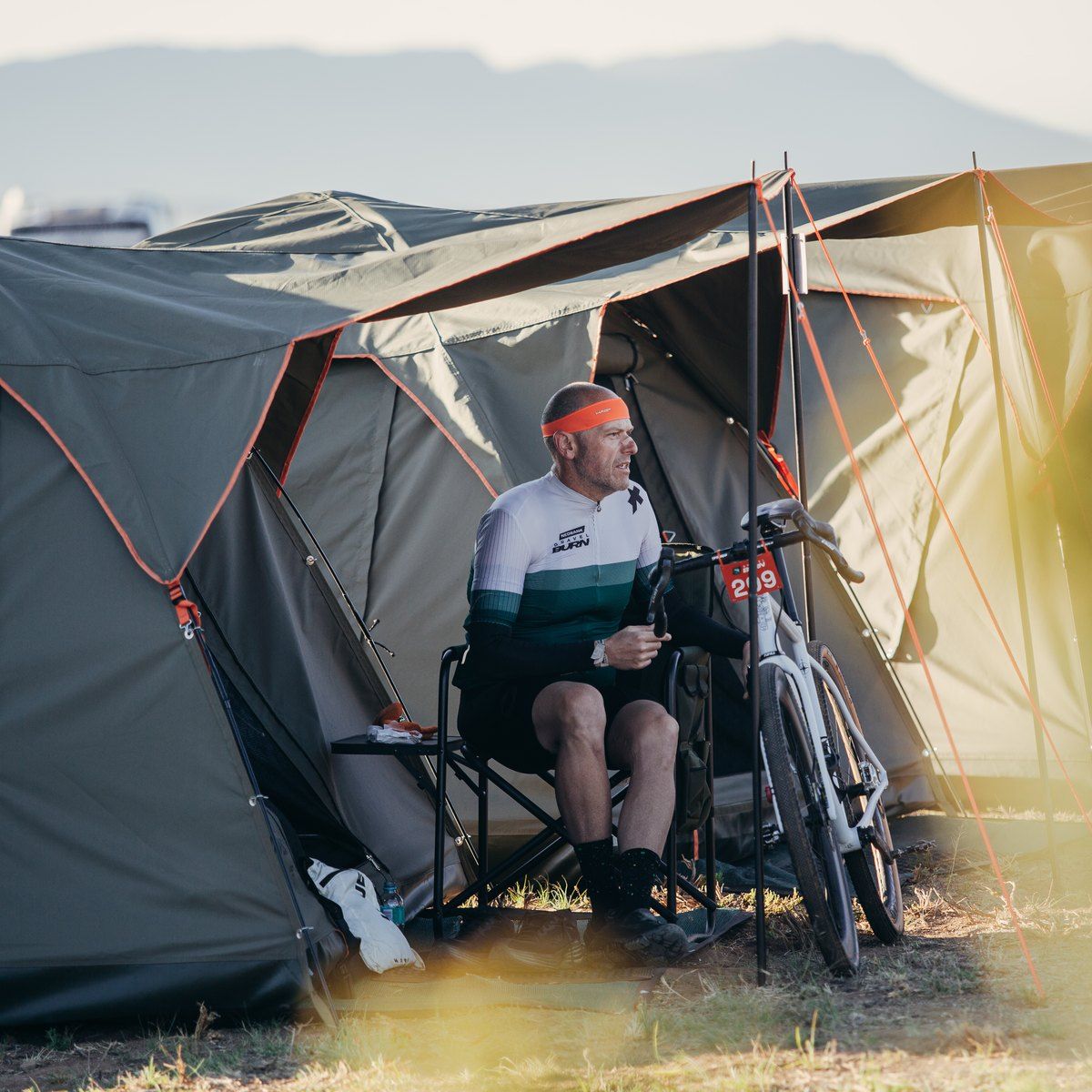 A rider relaxing in a camping chair outside his tent