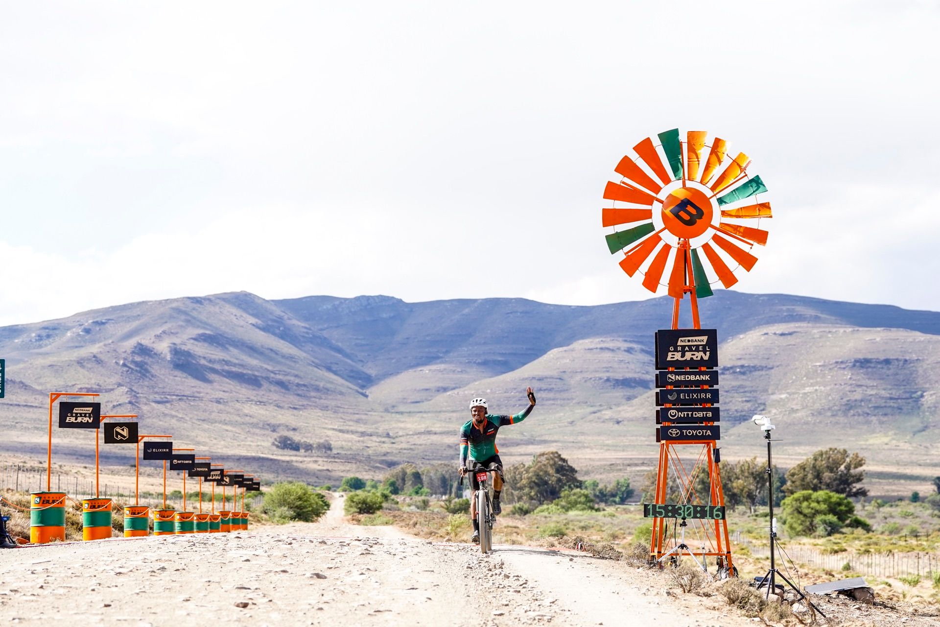 A rider waving as he reaches the orange windmill at the finish line