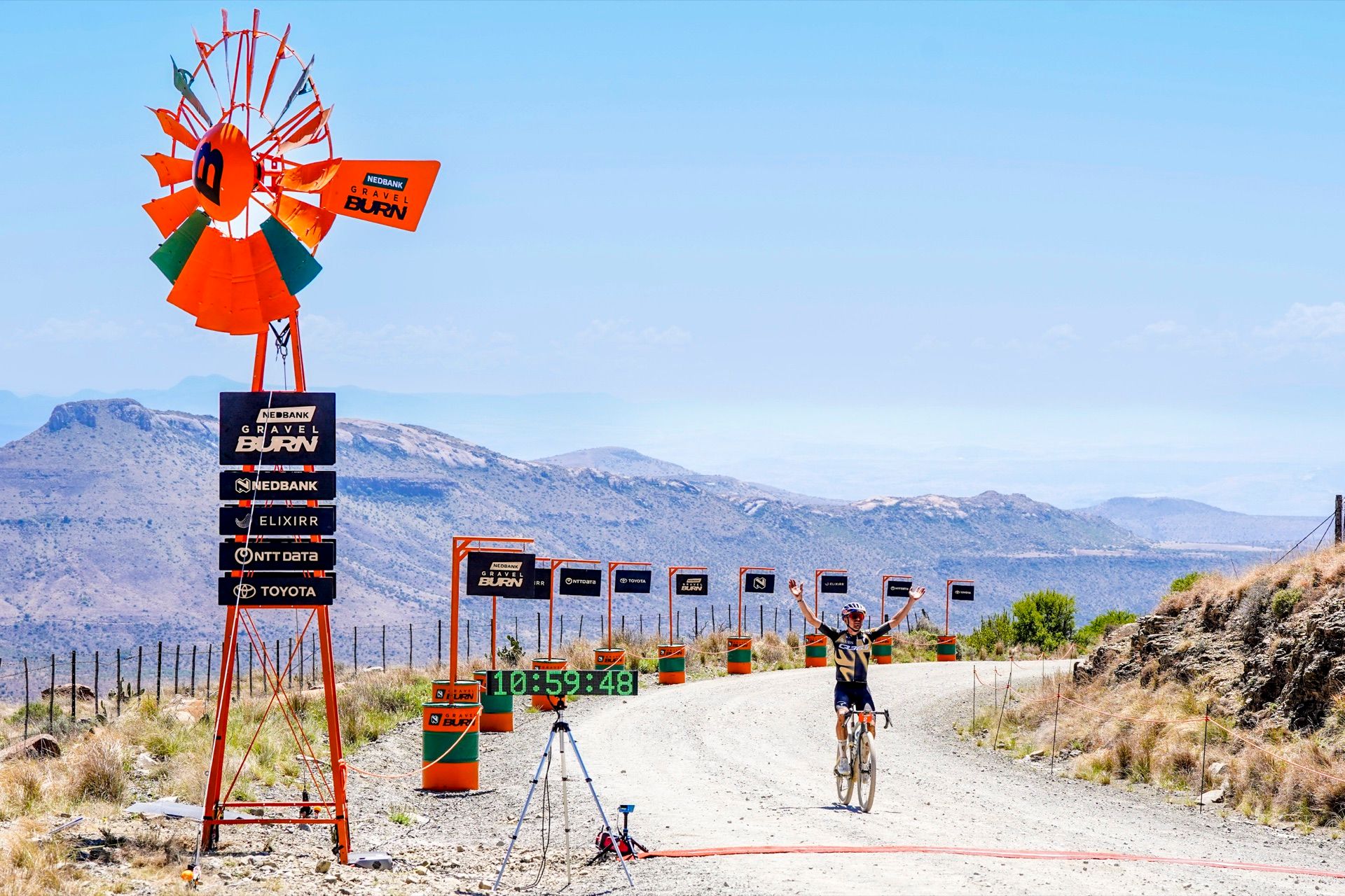 A rider celebrating at the orange windmill finish at the top of Swaershoek Pass
